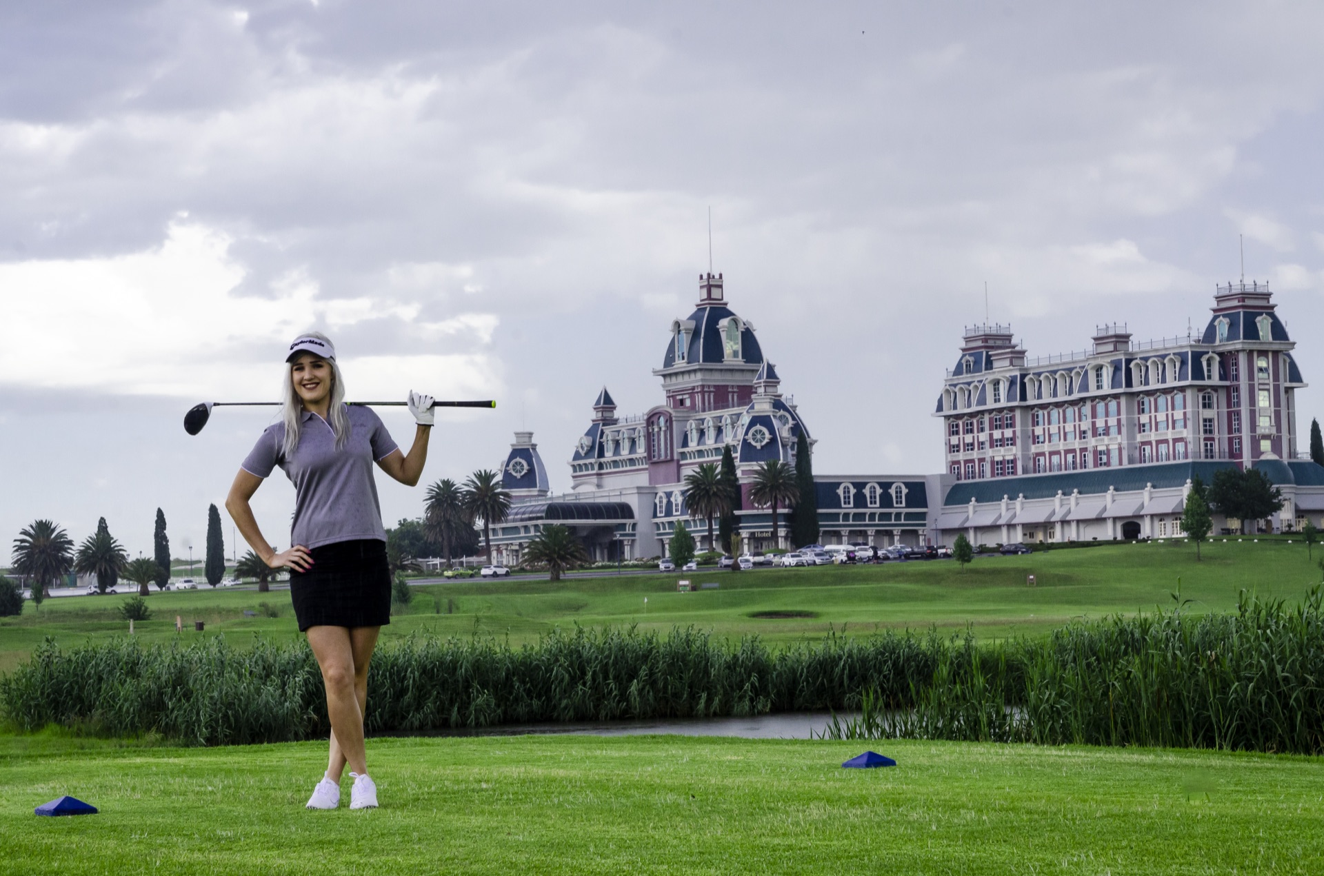 Golfer poses on the tee with the grand hotel behind at Graceland, Secunda