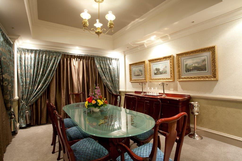 Presidential Suite dining room with glass-top table and floral centrepiece at Walmont Hotel at Graceland, Secunda